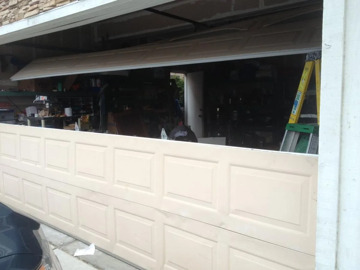 Buckled garage door panel showing horizontal crease damage requiring garage door section replacement