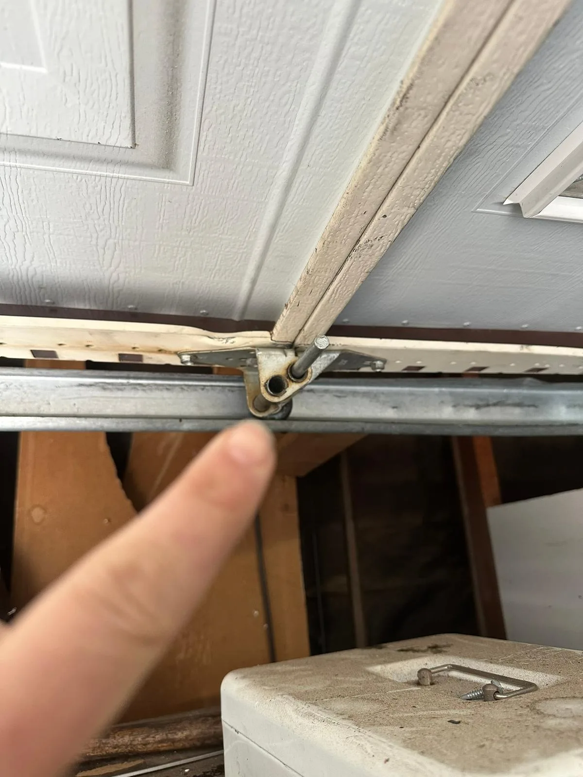Worn garage door hinge requiring replacement during repair service